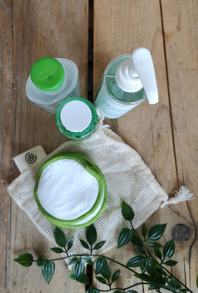 Reusable face pads with bottles on wooden table